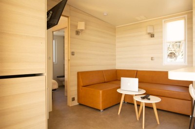 Salle de bain moderne avec meuble en bois clair, lavabo, miroir et douche vitrée équipée d'une pomme de douche.