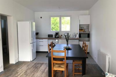 Chambre avec lits superposés, grandes fenêtres laissant entrer la lumière naturelle et parquet clair.