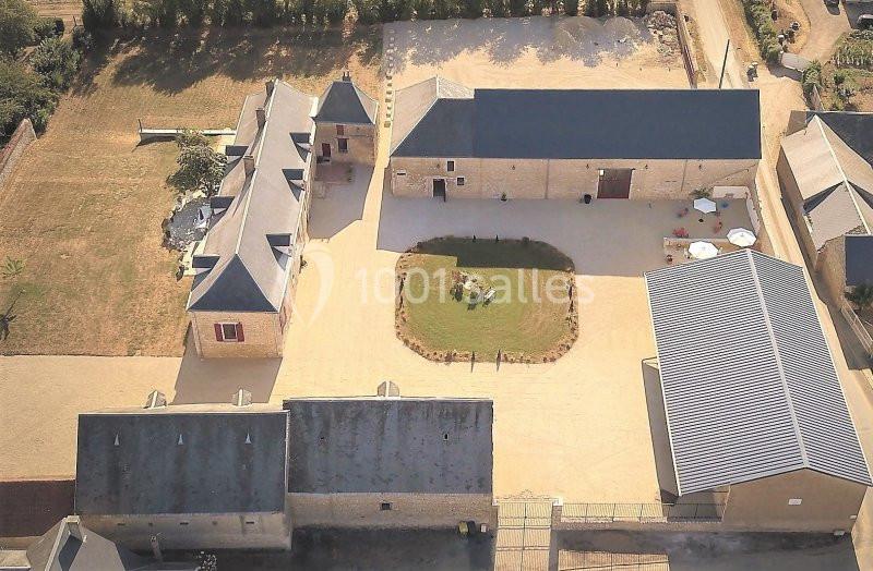 Vue aérienne d'un ensemble de bâtiments en pierre avec une cour centrale aménagée et des espaces verts.