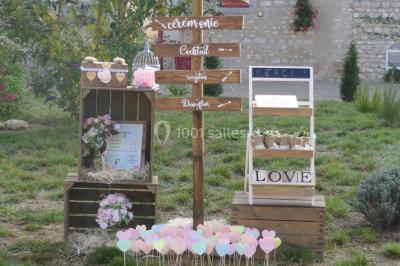 Décoration champêtre avec panneaux directionnels, fleurs, et accessoires pour un événement en extérieur.