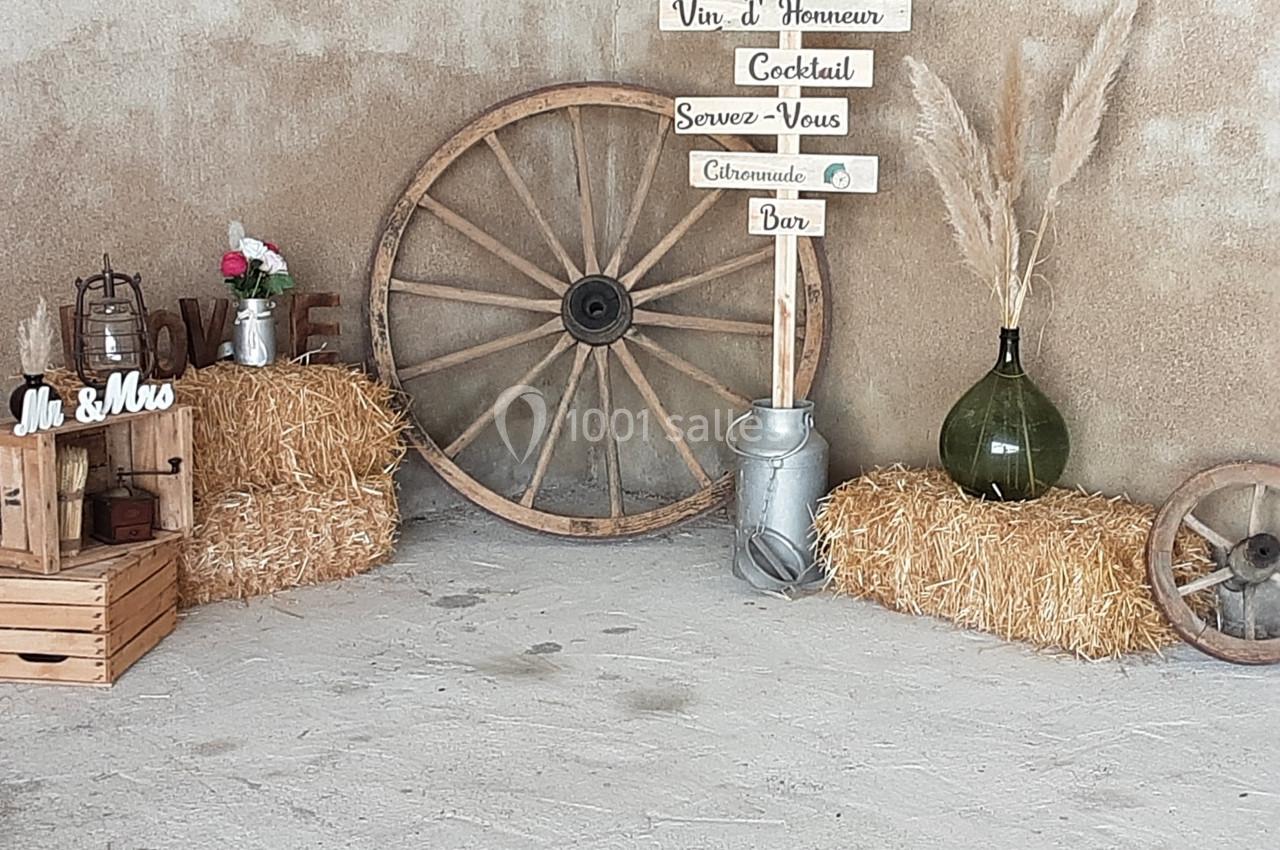 Décoration champêtre avec bottes de paille, roue en bois, pancartes directionnelles et accessoires rustiques.