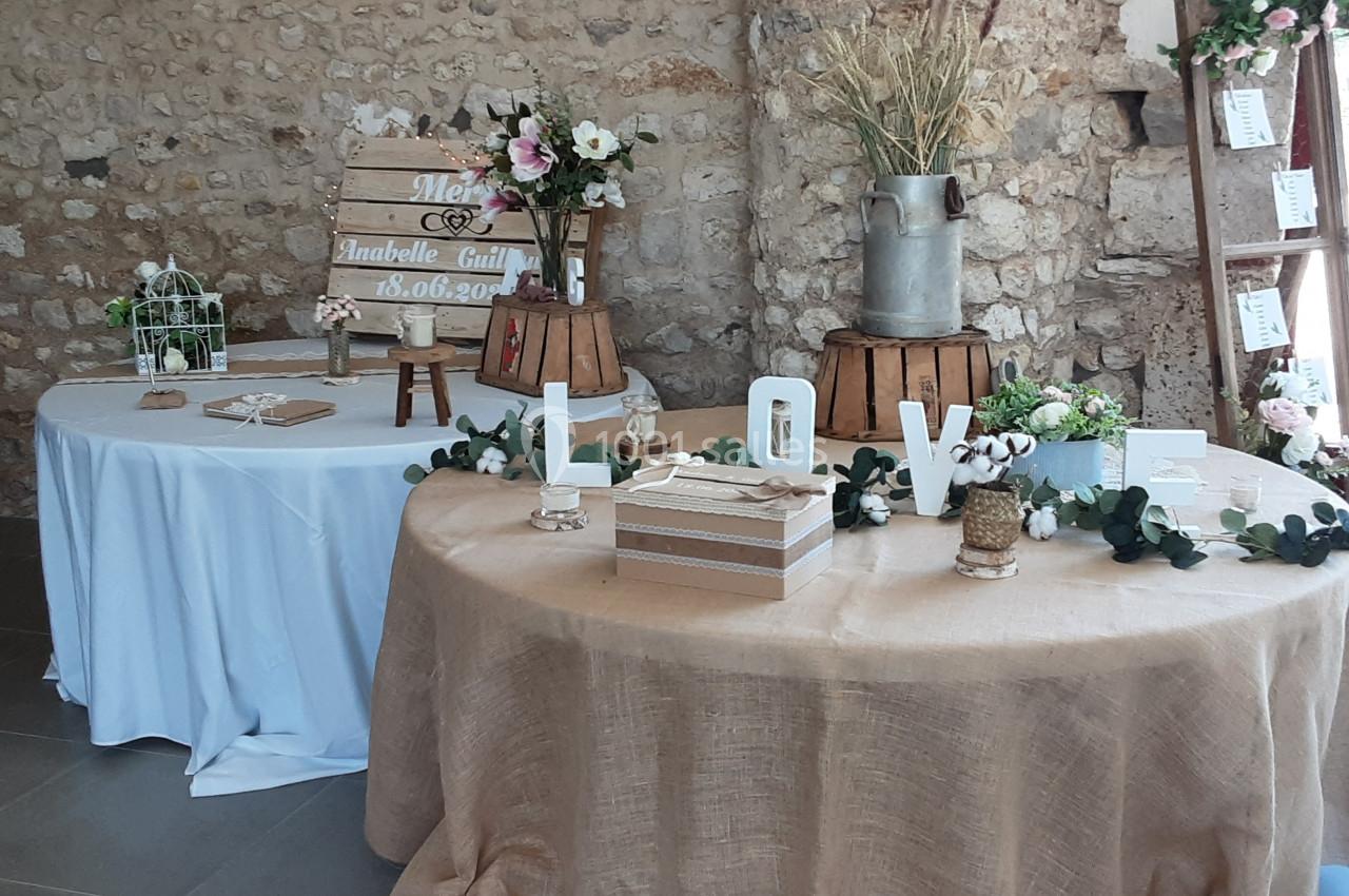 Tables décorées pour un mariage avec fleurs, lettres ’LOVE’, objets rustiques et panneau en bois personnalisé.