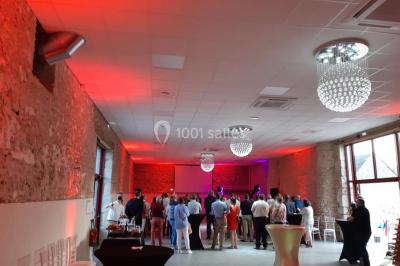 Un groupe de personnes sur scène lors d'une remise de prix dans une salle avec un mur en pierre et un écran de projection.