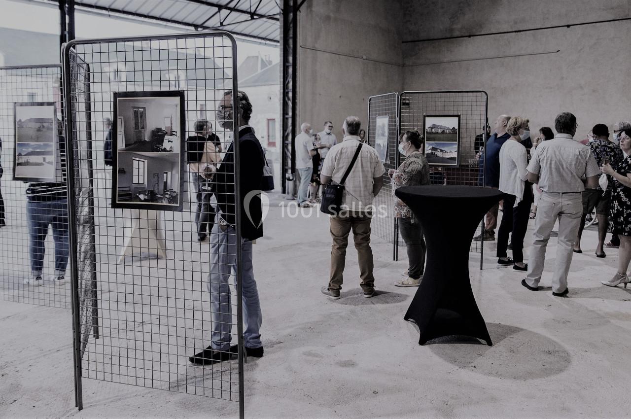 Des personnes visitent une exposition de photographies dans un espace intérieur avec des grilles d'affichage.