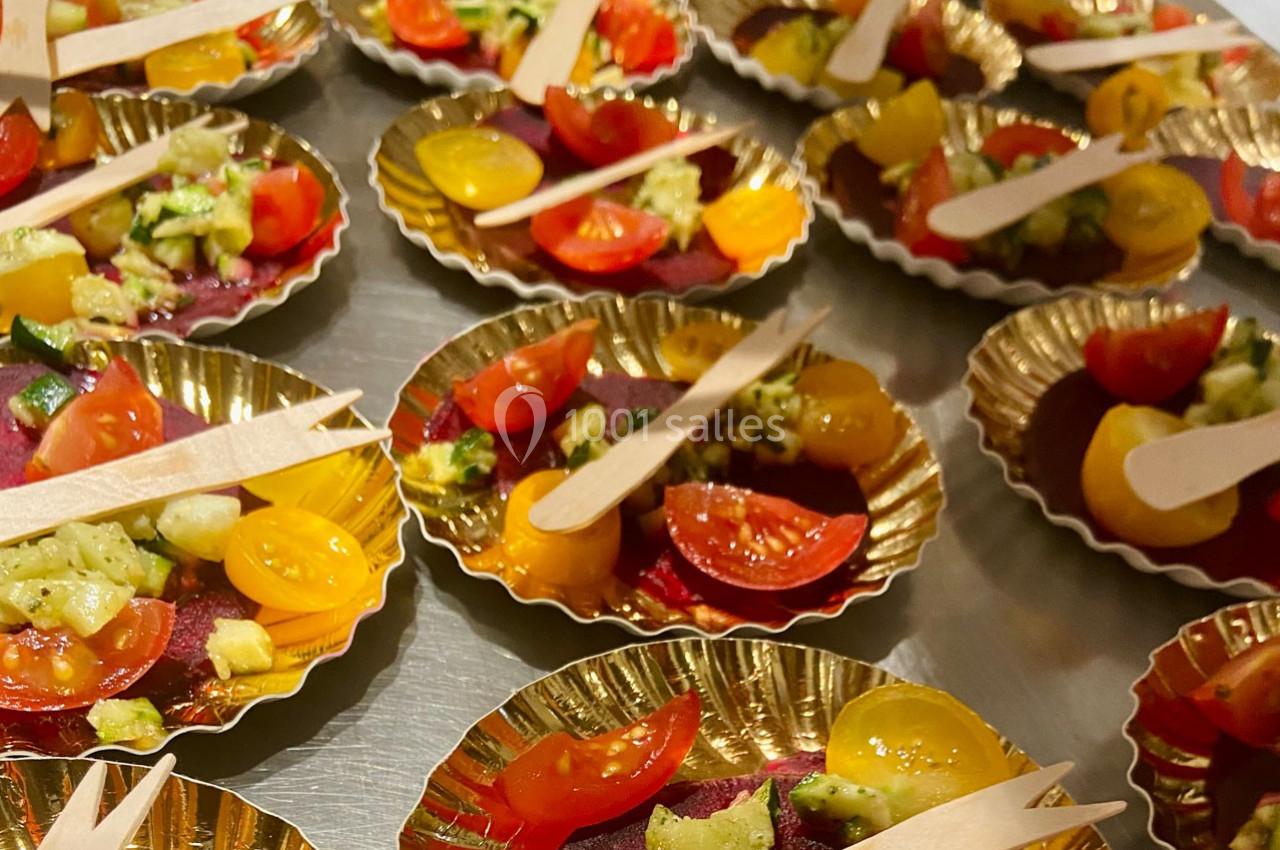Assiettes dorées contenant des morceaux de tomates cerises colorées et de légumes, accompagnés de petites fourchettes en…