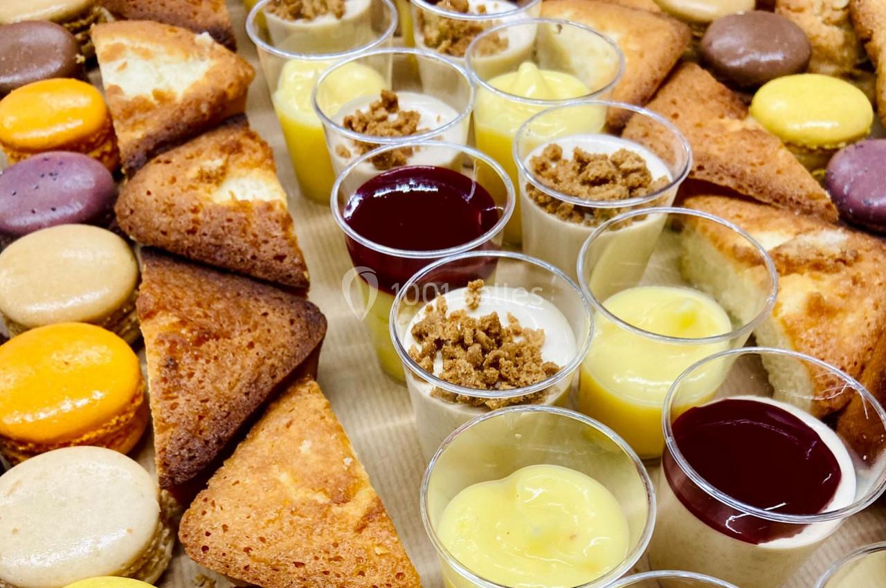 Plateau de desserts variés comprenant macarons, parts de gâteau et verrines de mousses et crèmes.