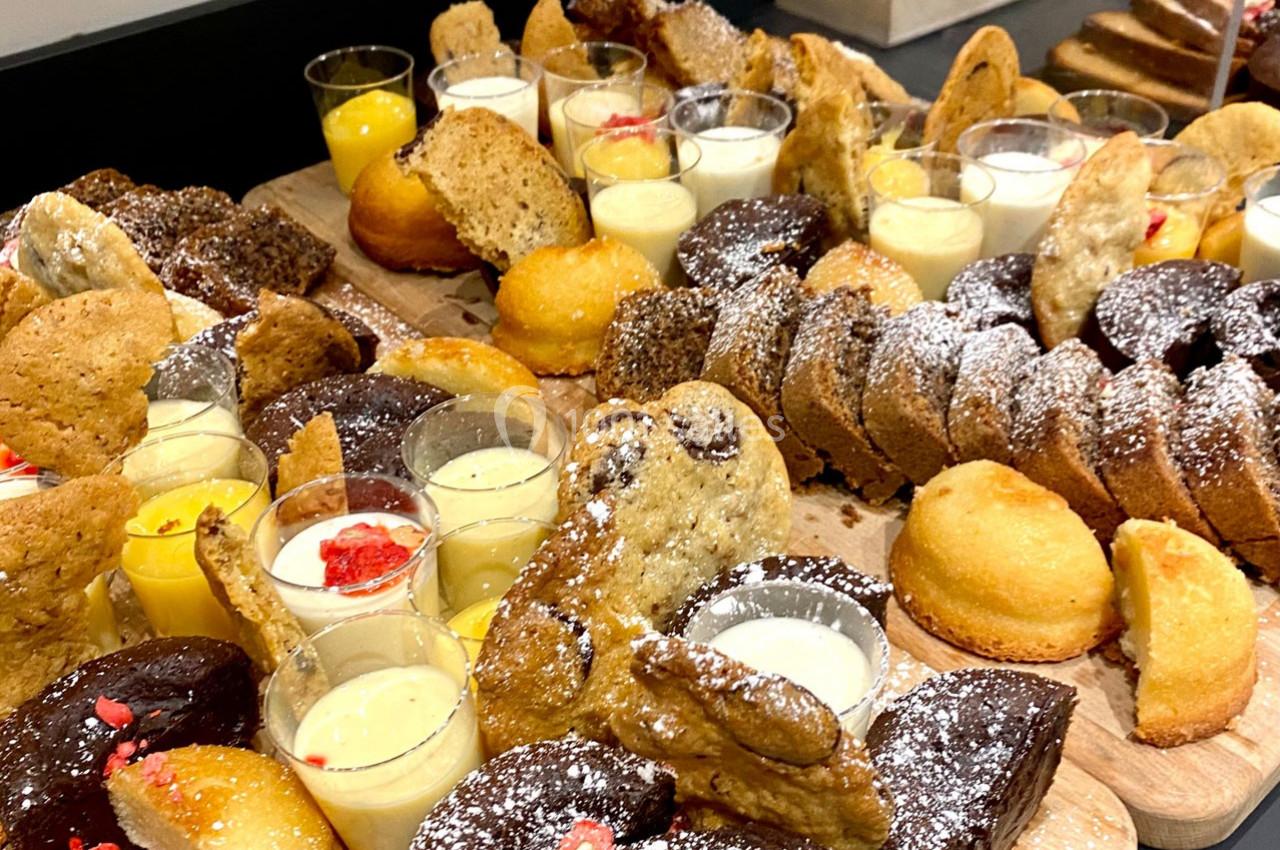 Plateau de desserts variés comprenant gâteaux, biscuits, verrines de crème et pâtisseries saupoudrées de sucre glace.