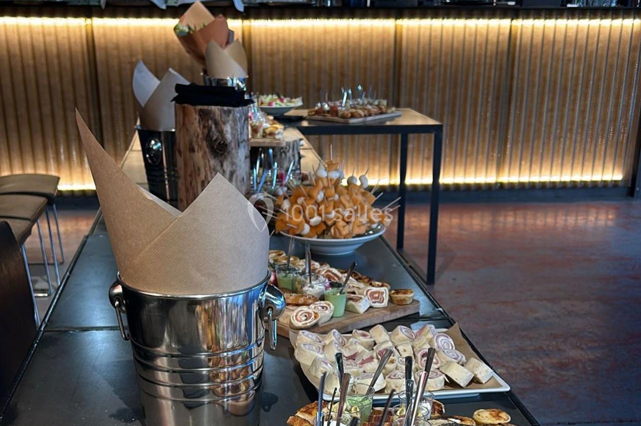 Buffet avec divers amuse-bouches et plats disposés sur des tables dans un espace intérieur éclairé.