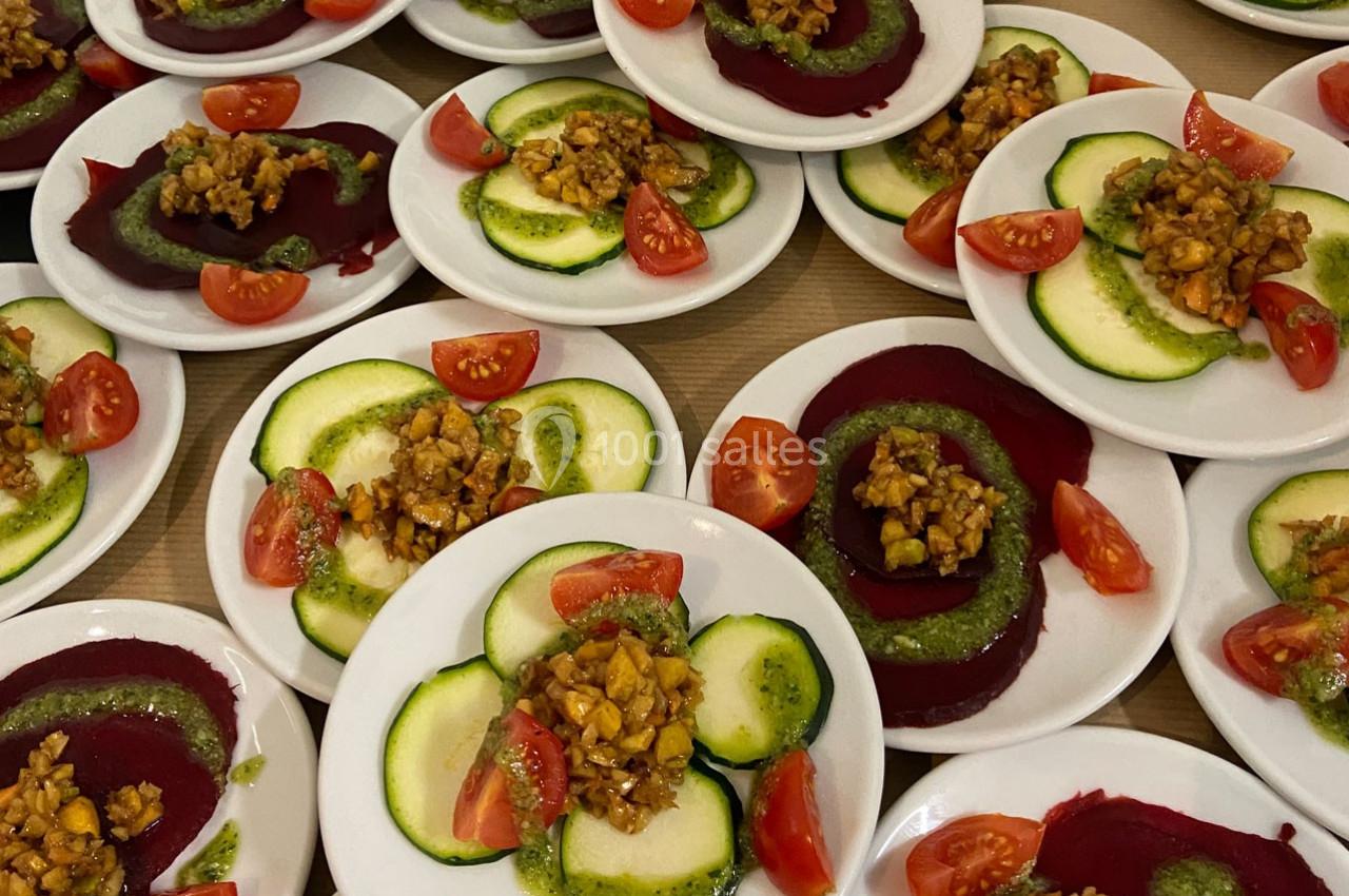 Assiettes garnies de tranches de betterave et courgette, tomates cerises et noix avec sauce verte.