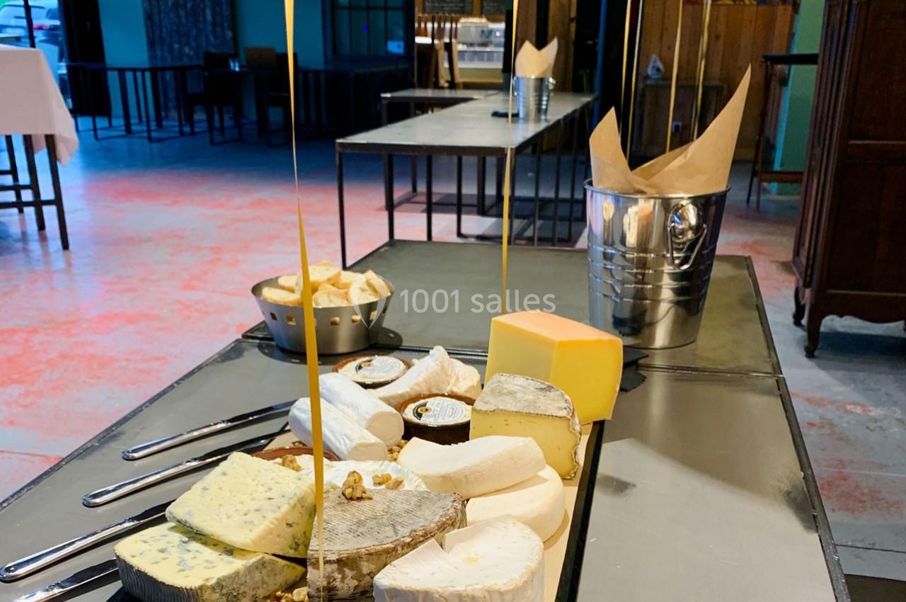 Plateau de fromages variés sur une table, avec du miel coulant d'une hauteur, dans un cadre intérieur.