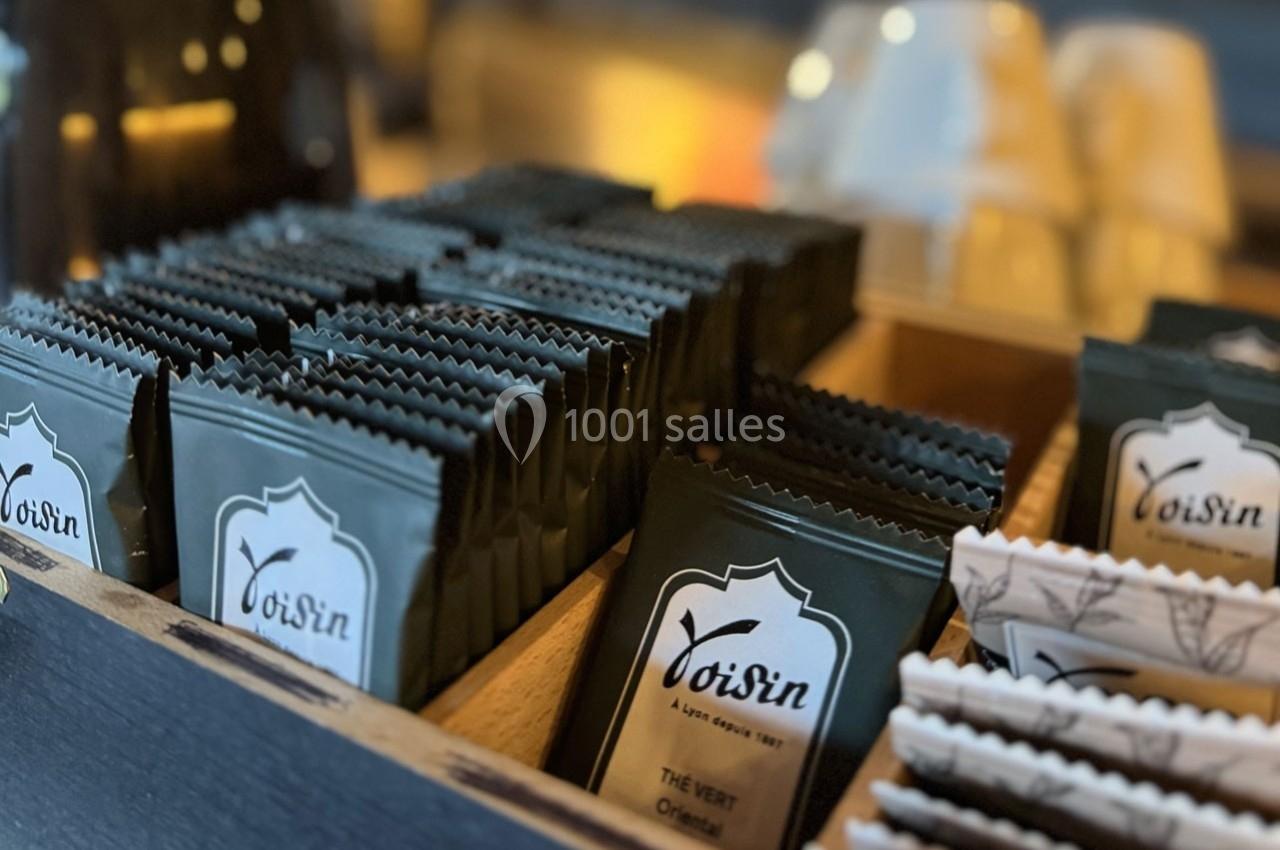 Sachets de thé alignés dans une boîte en bois, éclairés par une lumière chaude en arrière-plan.