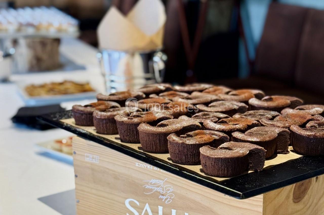 Plateau de fondants au chocolat disposés sur une boîte en bois, avec une table de buffet en arrière-plan.