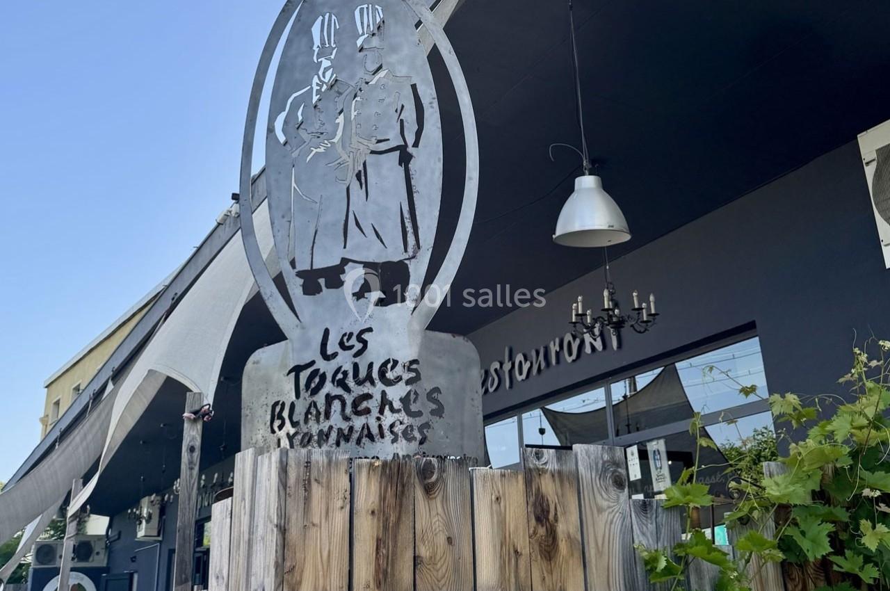 Sculpture métallique représentant deux chefs cuisiniers avec l'inscription ’Les Toques Blanches Lyonnaises’ devant un…