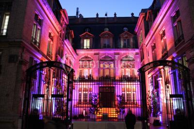 Salle de réunion avec table en bois, chaises noires, mur rouge décoré et écran mural éteint.