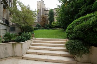 Salle de réunion avec table en bois, chaises noires, mur rouge décoré et écran mural éteint.