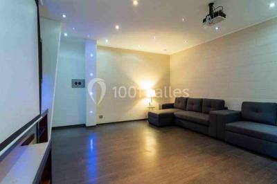 Vue panoramique sur une ville côtière avec des bâtiments, des arbres, la mer et des collines à l'horizon sous un ciel dégagé.