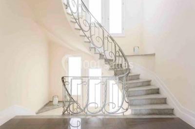 Vue panoramique sur une ville côtière avec des bâtiments, des arbres, la mer et des collines à l'horizon sous un ciel dégagé.