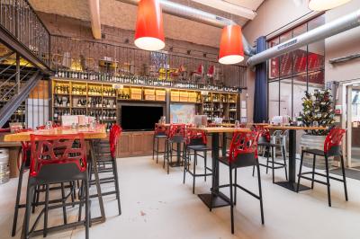 Salle de restaurant moderne avec tables noires, chaises rouges translucides et mur en pierre apparente.