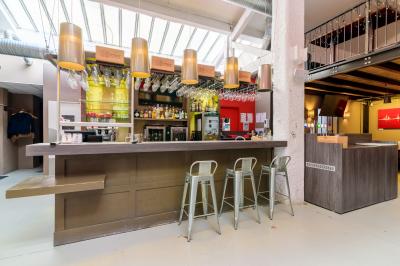 Salle de restaurant moderne avec tables noires, chaises rouges translucides et mur en pierre apparente.