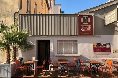 Salle de restaurant moderne avec tables noires, chaises rouges translucides et mur en pierre apparente.