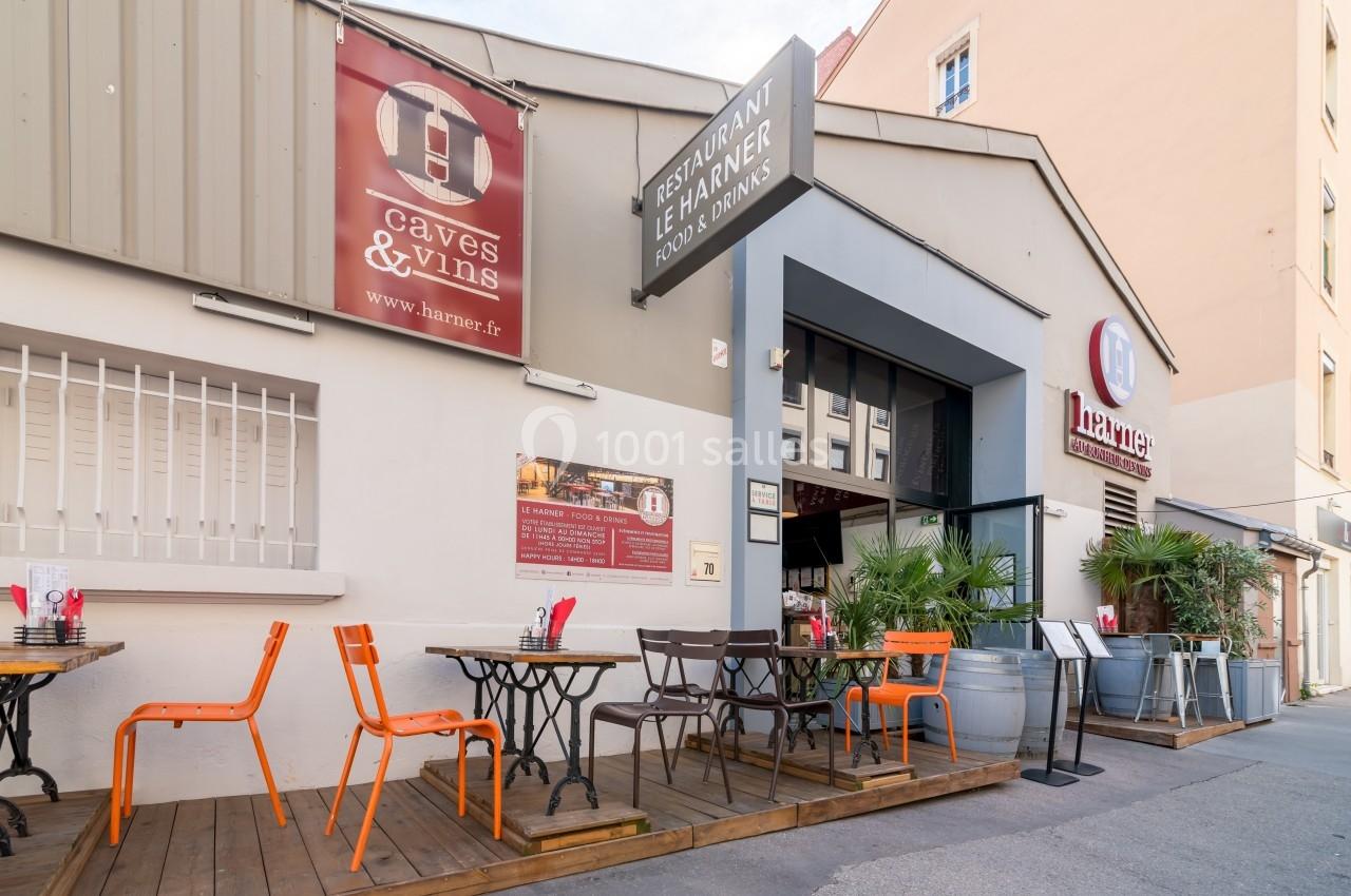 Terrasse d'un restaurant avec tables et chaises colorées, située devant une façade beige avec enseignes visibles.