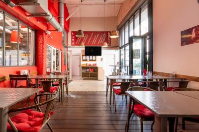 Salle de restaurant moderne avec tables noires, chaises rouges transparentes et décoration murale contemporaine.