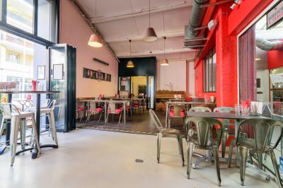 Salle de restaurant moderne avec tables noires, chaises rouges transparentes et décoration murale contemporaine.