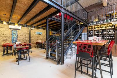 Salle de restaurant moderne avec tables noires, chaises rouges transparentes et décoration murale contemporaine.