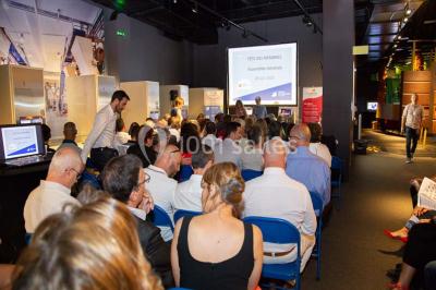 Verres de vin rouge et blanc sur un tonneau en bois, accompagnés de chocolats assortis disposés sur des tablettes.