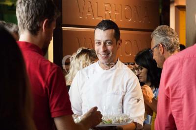 Verres de vin rouge et blanc sur un tonneau en bois, accompagnés de chocolats assortis disposés sur des tablettes.