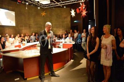 Verres de vin rouge et blanc sur un tonneau en bois, accompagnés de chocolats assortis disposés sur des tablettes.