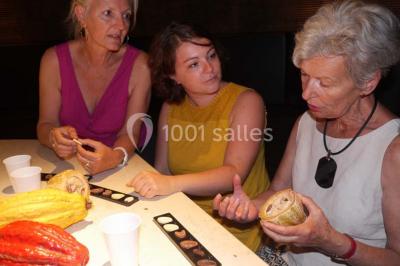 Verres de vin rouge et blanc sur un tonneau en bois, accompagnés de chocolats assortis disposés sur des tablettes.