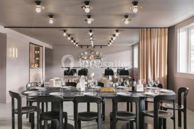 Salle à manger moderne avec grande table noire, chaises assorties, vaisselle dressée et décor mural en assiettes.