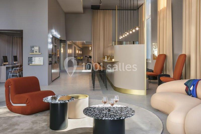 Espace intérieur moderne avec fauteuils design, tables basses, comptoir arrondi et éclairage suspendu.