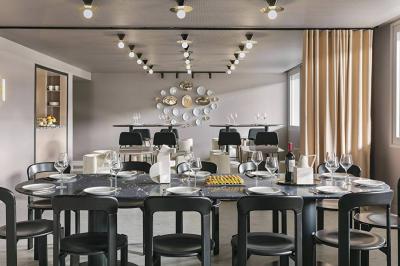 Salle à manger moderne avec grande table noire, chaises assorties, vaisselle dressée et décor mural en assiettes.