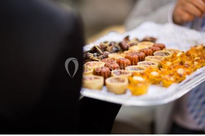 Kiosque décoré de fleurs blanches au bord d'un lac avec une fontaine, sous un ciel dégagé.