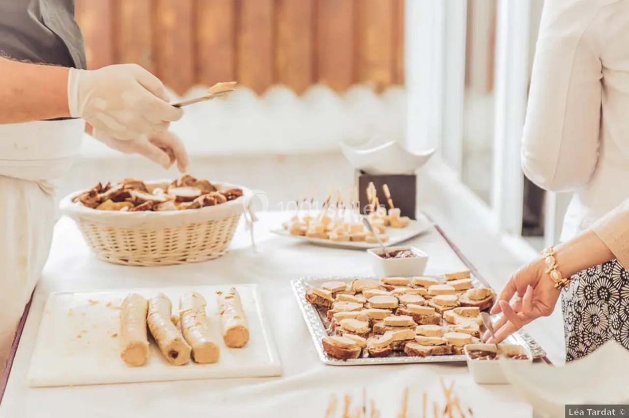 Personnes préparant et disposant des amuse-bouches sur une table garnie de plateaux et d'un panier de pain.