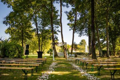 Kiosque décoré de fleurs blanches au bord d'un lac avec une fontaine, sous un ciel dégagé.