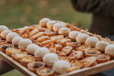 Plateau doré contenant des cuillères individuelles garnies de petites portions de nourriture raffinée.