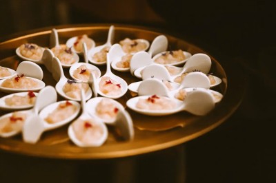 Plateau doré contenant des cuillères individuelles garnies de petites portions de nourriture raffinée.