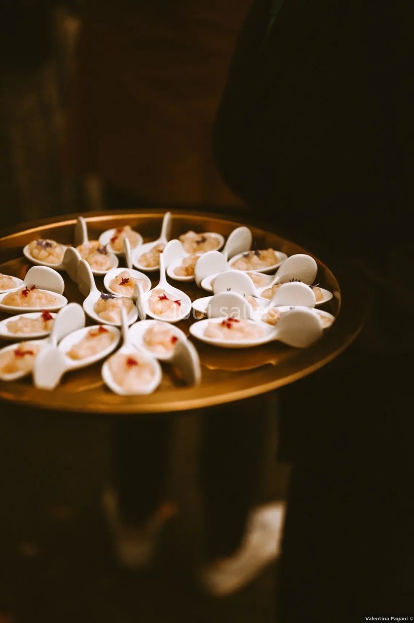 Plateau doré contenant des cuillères individuelles garnies de petites portions de nourriture raffinée.