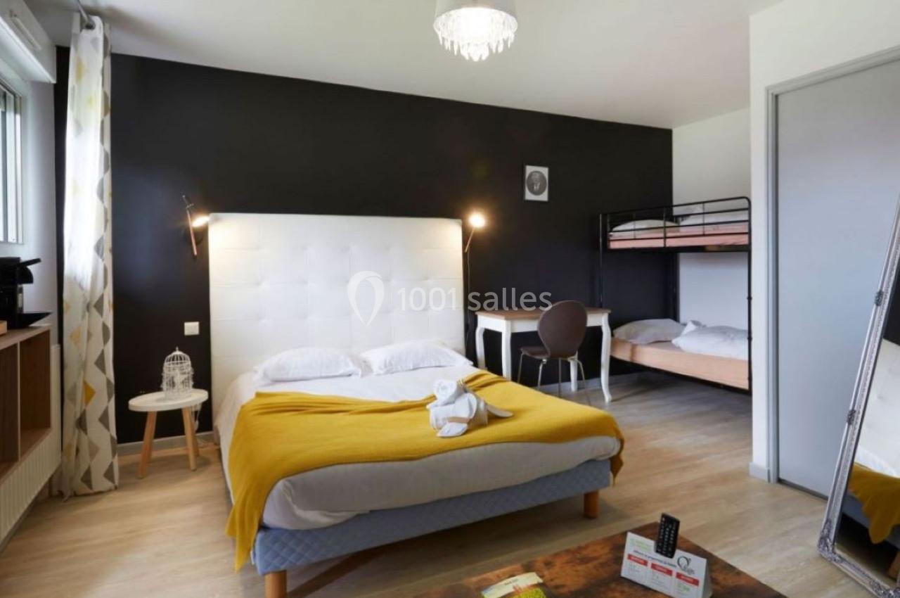 Chambre avec lit double, lits superposés, bureau, miroir, et décoration moderne sur fond de mur noir.