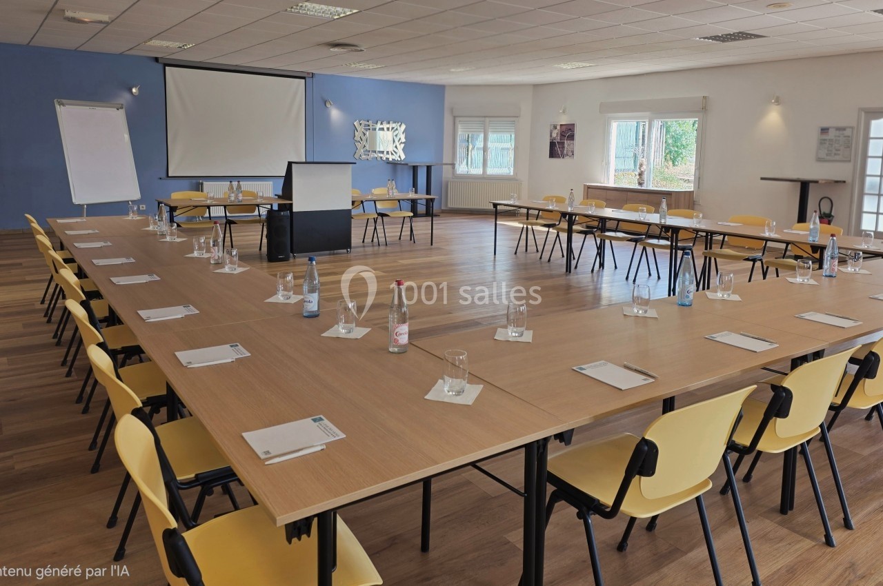 Salle de réunion lumineuse aménagée en U avec tables, chaises jaunes, écran de projection et paperboard.