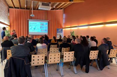 Vue aérienne d'un château médiéval entouré de verdure, au cœur d'une petite ville avec des habitations et des routes.