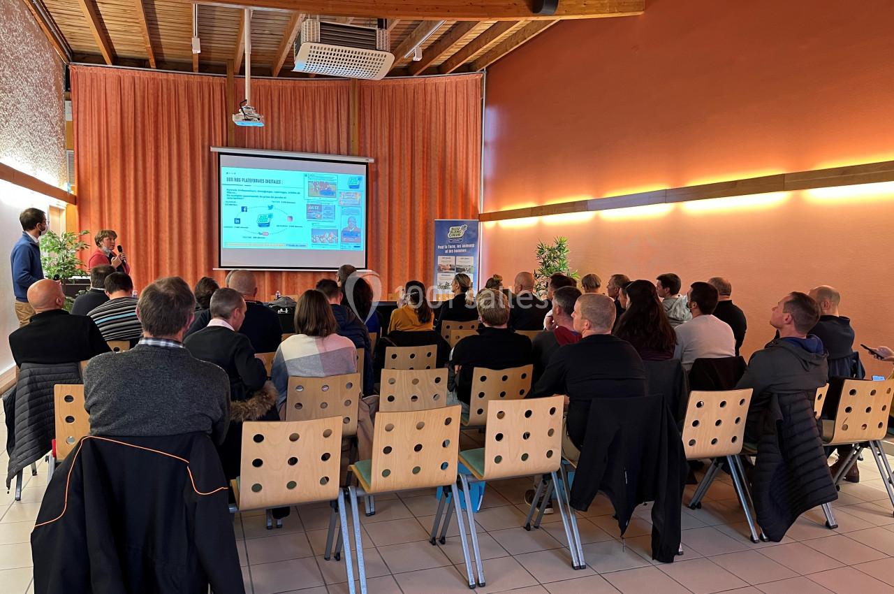 Un groupe de personnes assises dans une salle regardant une présentation projetée sur un écran.