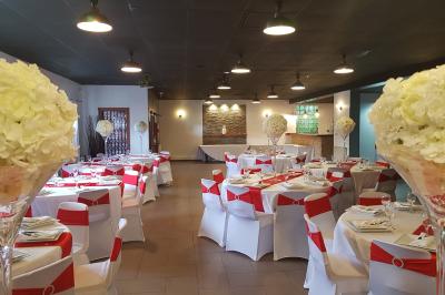 Salle spacieuse avec carrelage au sol, murs clairs, plafond noir, tables et chaises dispersées.