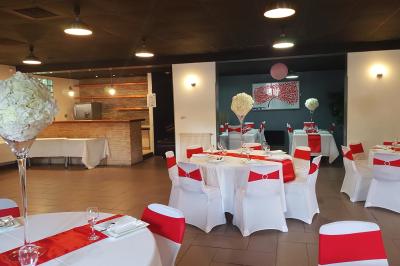 Salle spacieuse avec carrelage au sol, murs clairs, plafond noir, tables et chaises dispersées.