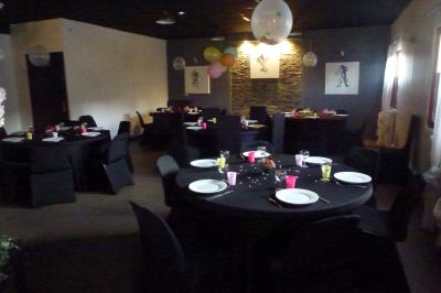 Salle spacieuse avec carrelage au sol, murs clairs, plafond noir, tables et chaises dispersées.