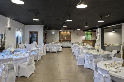 Salle spacieuse avec carrelage au sol, murs clairs, plafond noir, tables et chaises dispersées.