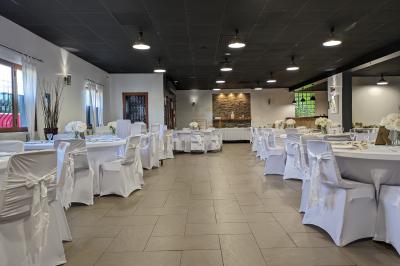 Salle spacieuse avec carrelage au sol, murs clairs, plafond noir, tables et chaises dispersées.